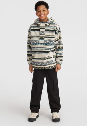 Fleece pullover met een capuchon, voorzien van een gestreept patroon in beige, blauw en groen. Gecombineerd met zwarte cargobroek en beige laarzen.