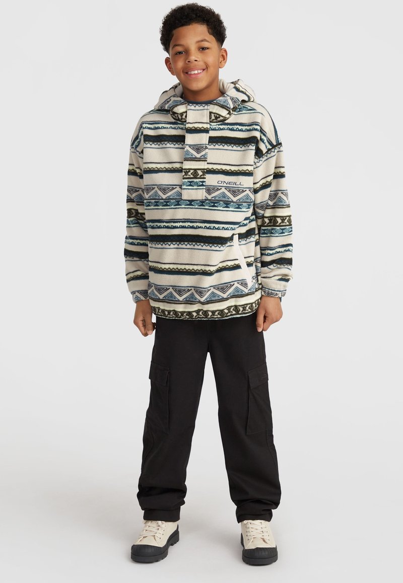 Fleece pullover met een capuchon, voorzien van een gestreept patroon in beige, blauw en groen. Gecombineerd met zwarte cargobroek en beige laarzen.