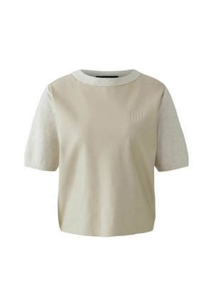 Beige t-shirt met korte, lichtgrijze mouwen. Bevat een ronde hals en een subtiel reliëf logo op de voorkant. Glad en zacht textiel.