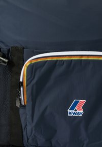 Sac messager K-Way bleu marine avec une poche avant zippée. Présente des accents rayés vifs et un logo. Tissu texturé, construction durable.