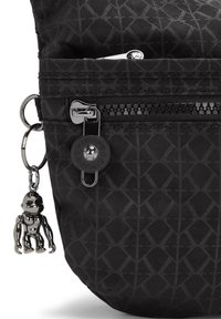 Black fabric bag with geometric pattern, featuring a zippered pocket, round button, and a silver keychain monkey charm.
