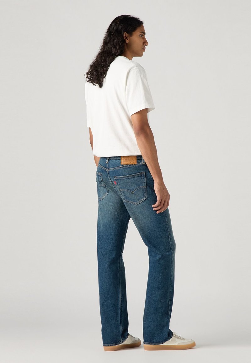Lättviktig vit T-shirt som kombineras med mid rise raka jeans i mörkblått med subtila blekningar, som har två bakfickor och en varumärkesetikett.
