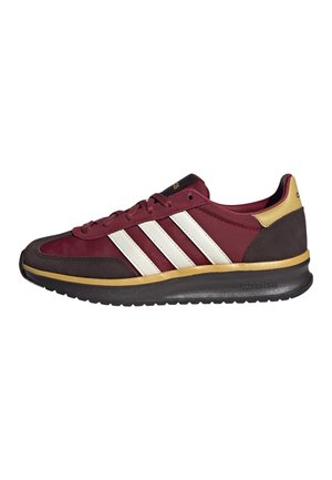 Zapatilla burdeos y marrón oscuro con rayas blancas, detalle dorado, suela negra y diseño con cordones, vista lateral sobre fondo blanco.