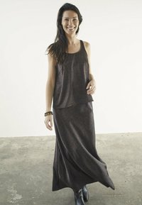 Brun leopardprint maxi kjole med en svævende silhuet og ærmeløs top, suppleres af et tekstureret sort armbånd og sorte støvler.