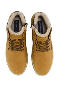 Bottes chevillières en cuir marron avec une doublure en fourrure douce, dotées d'un système de laçage, de lacets sombres contrastants et d'une semelle en caoutchouc texturée.