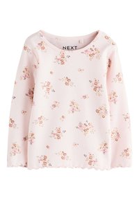 Light pink top with floral patterns, ribbed texture, scalloped hem, and long sleeves. Brand label "NEXT" visible near the neckline.