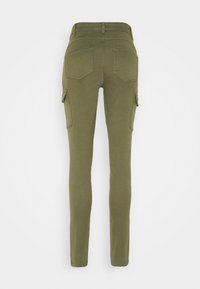 Pantalon slim fit vert olive avec poches arrière et poches cargo latérales, vu de dos sur fond blanc.