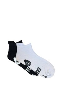 Calze alla caviglia in bianco e nero con design contrastanti. La calza nera ha un logo bianco, mentre la calza bianca mostra testo e grafica nera.