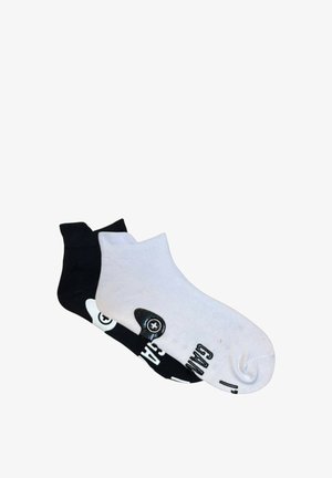 Black and white ankle socks featuring contrasting designs. The black sock has a white logo and the white sock displays black text and graphic.
