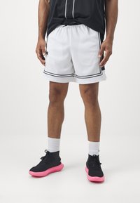 White mesh basketball shorts with black trim and an elastic waistband, paired with black and pink sneakers and white athletic socks.