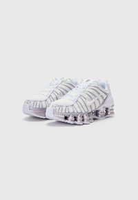 Baskets de sport blanches avec des accents argentés brillants, un dessus en mesh et un design de semelle unique en forme de ressort. Dispose de lacets et d'un logo sur la languette.
