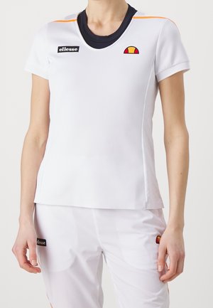 Kvinde model iført hvid atletik T-shirt med orange detaljer og matchende bukser med ellesse-mærkets logoer på bryst og lår.
