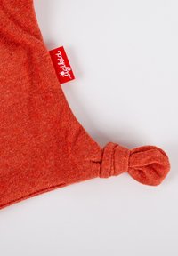 Orange cotton hat with a knotted tip and a red tag displaying "bigkid". The fabric has a soft texture and a slight heathered pattern.