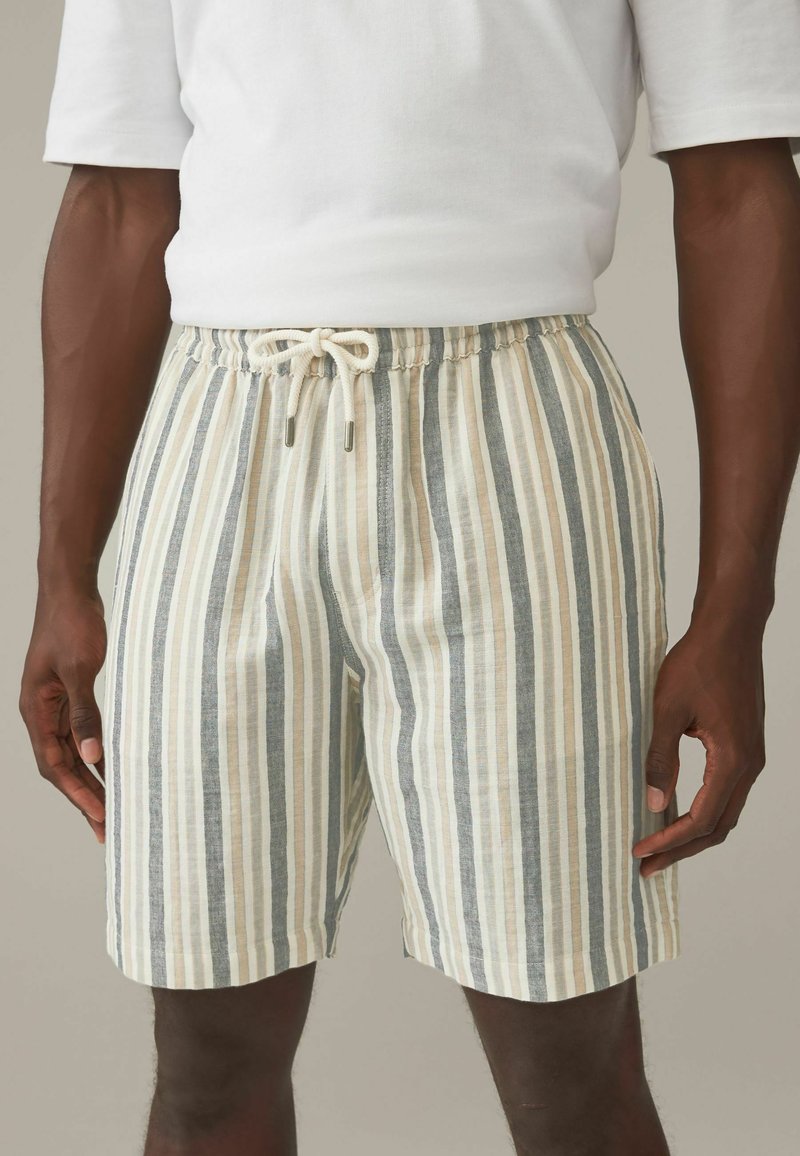 Shorts rayés en beige, bleu et crème. Fabriqués en tissu léger avec une taille élastique et un cordon de serrage ajustable.