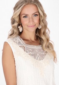 Top i off-white med blondebesætning, der har et tekstureret stof med blomster mønstre, gennemsigtig halsudskæring og blød, svævende silhuet.