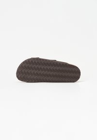Semelle en caoutchouc marron avec un motif de semelle ondulée et un bord arrondi. Présente une surface plate et texturée adaptée aux chaussures décontractées.