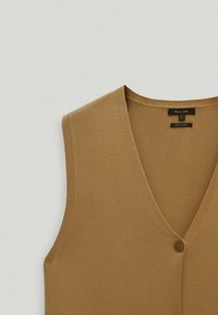 Brauner ärmelloser Stricktop mit V-Ausschnitt, der eine einzelne Knopfverschlüsse auf der Vorderseite und eine glatte Textur aufweist. Etikett liest "Hergestellt in der Türkei."