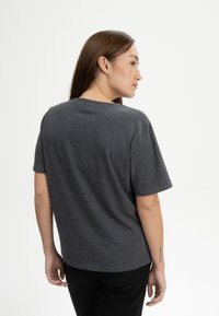 Grijze T-shirt met korte mouwen, met een relaxte pasvorm en ronde hals, gemaakt van zacht materiaal. De achterkant is eenvoudig, zonder zichtbare logo's of patronen.