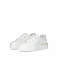 Zapatilla blanca con un upper suave, acentos dorados cerca del talón y un diseño de logo perforado. Cuenta con una suela plana y gruesa y un sistema de lazado en la parte delantera.
