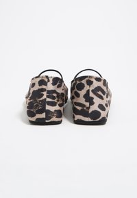 Zapatos deslizantes de estampado de leopardo con parte superior de tela suave, forma redondeada, suela de goma negra y parte posterior elástica para poner y quitar fácilmente.