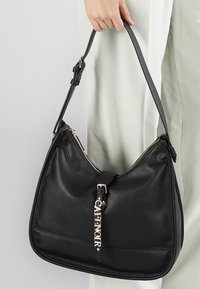 Sort læder hobo taske med pebble tekstur. Har en guldrumpe og hardware, med et mærkenavn tag fastgjort til lynlåsen.