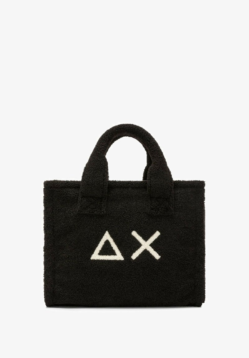 Borsa tote di tessuto nero e soffice con due manici corti. Presenta simboli geometrici bianchi: un triangolo e una 'X' sul davanti.