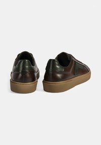 Leder-Sneaker in Dunkelbraun mit grünen Akzenten, mit niedrigem Profil, strukturiertem Obermaterial und beiger Gummisohle.