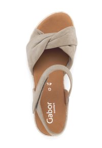 Sandal in suede beige chiaro con design superiore annodato, punta aperta e soletta color cammello. Caratterizzato da una cintura laterale regolabile e una suola testurizzata.