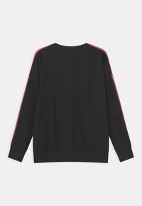 Sweat-shirt noir à manches longues, col rond, avec des rayures roses le long des épaules. Tissu doux avec une coupe décontractée.