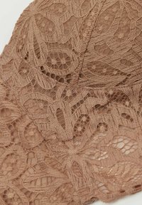 Brazylka w jasnobrązowym kolorze z misternymi wzorami kwiatowymi, z finezyjnie teksturowanej tkaniny oraz półprzezroczystymi detalami. Wykonana z miękkich, delikatnych materiałów.