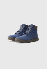 Par de botas de tornozelo em suede azul com atacadores, solas escuras e gola almofadada castanha, em fundo branco.