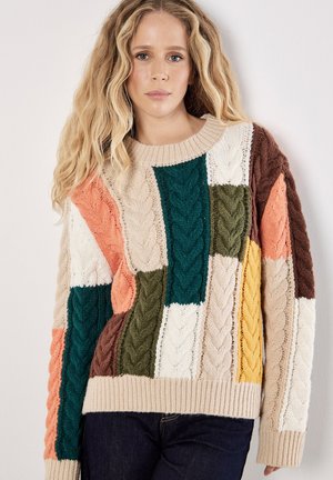 Sweter dzianinowy z wzorem patchworkowym w różnych kolorach: kremowym, zielonym, pomarańczowym i brązowym. Teksturowane wzory warkoczowe i ściągacz na dole.