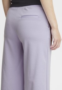 Lila wijde broek van zacht materiaal, met een achterzak en een gladde textuur. De tailleband is elastisch voor comfort.