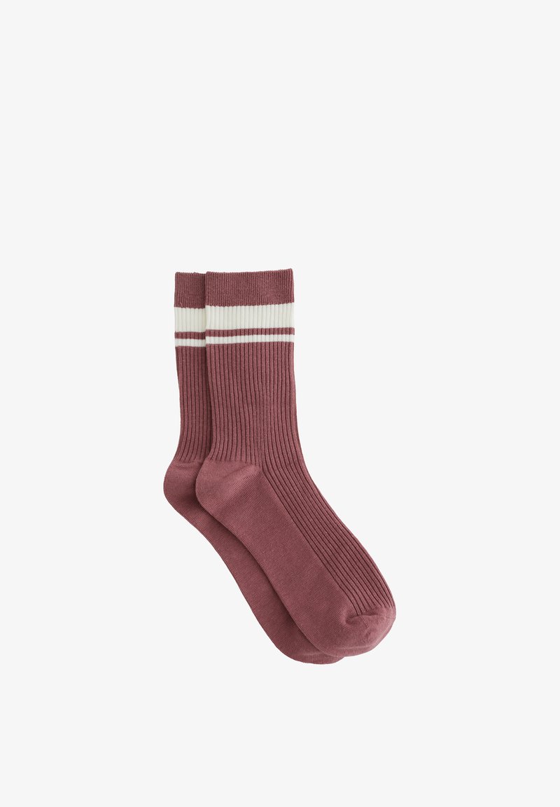Paire de chaussettes côtelées mi-mollet de couleur rose atténuée avec des rayures blanches et roses près du haut, posées à plat sur un fond blanc.