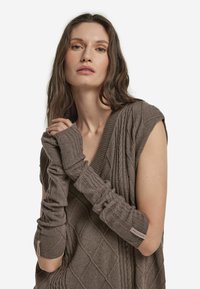 Prosty sweter bez rękawów w kolorze taupe, z teksturowanym wzorem diamentowym, prążkowanym dekoltem i długimi opaskami na ramiona z logo marki.