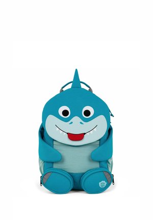 Blue children's backpack shaped like a smiling shark with fins, big eyes, and a red tongue sticking out.