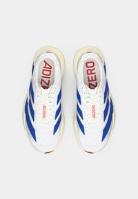 Une paire de chaussures de running blanches avec des rayures bleues, des semelles beiges et un logo "ADIZERO" rouge sur les semelles intérieures et les languettes, vue de dessus.