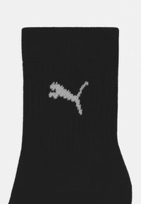 Calcetín de algodón negro hasta el tobillo con textura acanalada y un logotipo blanco de Puma tejido en el lateral.