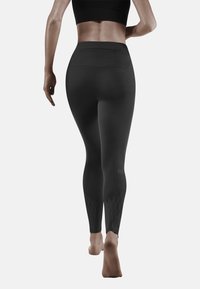Hoge zwarte leggings met een gladde textuur, voorzien van diamantpatronen bij de enkels en een subtiele ritszak op de achterkant van de taille.
