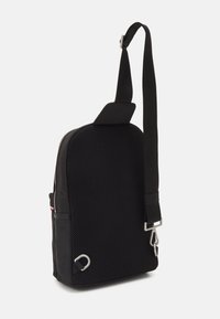 Zaino a tracolla nero con pannello posteriore in rete, spallacci regolabili, hardware argentato e scomparto principale con zip.