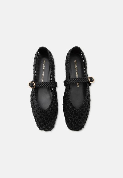 Ballerines Mary Jane tissées noires avec boucles dorées et marquage "Stuart Weitzman" sur les semelles intérieures, vues de dessus sur fond blanc.