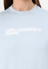 Világoskék pamut póló, bordázott környakkal, elöl fehér nyomtatott szöveggel: "KARL LAGERFELD JEANS".