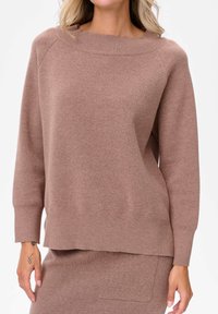 Brązowy sweter dzianinowy z szerokim dekoltem w łódkę, długimi rękawami raglanowymi, ściągaczami przy mankietach i luźnym krojem. Tekstura jest miękka i gładka.