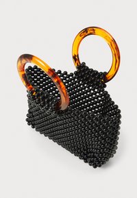 Črna biserna torbica s strukturirano obliko, opremljena z dvema okroglima ročajema iz želvje školjke. Teksturirana površina z okroglimi biseri.