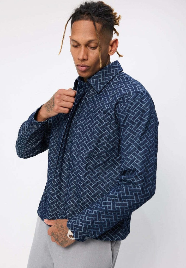Chemise boutonnée bleu marine avec un tissage à motifs géométriques, manches longues, col et coupe décontractée.