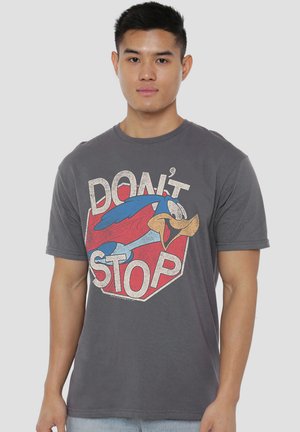 Junger Mann trägt ein graues T-Shirt mit einem retro Cartoon-Vogel und dem Text "DON'T STOP" auf rotem Stoppschild-Hintergrund.