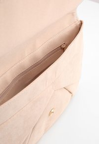 Beige látková kabelka s vnitřní kapsou na zip a zlatým drukem. Hladká textura s jemným, strukturovaným designem.