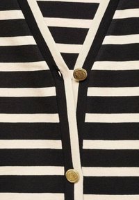 Tessuto a strisce orizzontali bianco e nero con scollatura a V e due bottoni decorativi dorati al centro.
