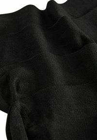Schwarzer Stoff mit einer glatten Textur, der sanfte Wellen und unterschiedliche Dicken aufweist. Das Material wirkt leicht und flexibel.
