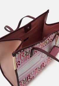 Stor tote-väska med vinröda handtag, inredning i ljusrosa, prydd med ett grått tyg med rosa geometriska mönster. Inkluderar en kedja och tillbehörsetikett.